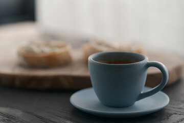 Espresso in blue cup with sandwiches with cream cheese on background