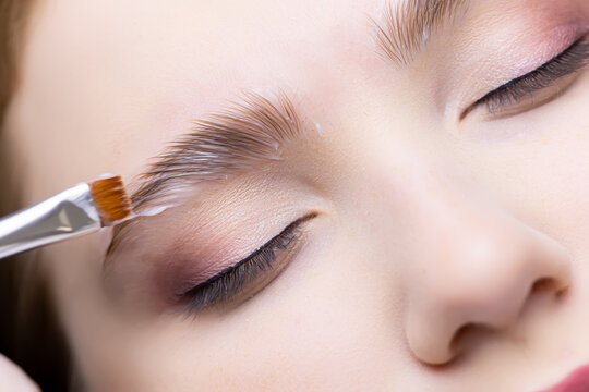 close-up of the eyebrows of the model on which the master applies laminating compositions with a brush