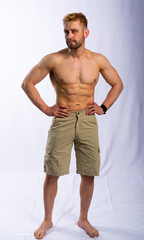 Fototapeta premium muscular man in shorts posing, shows, straining muscles. gray background