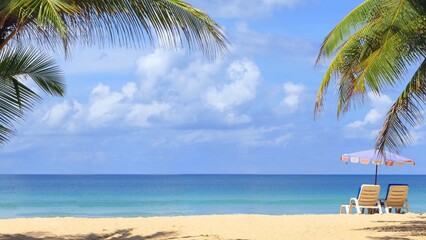 Beach with palm trees and umbrellas to sit and relax on a sunny day at Karon Beach, Phuket, Thailand.