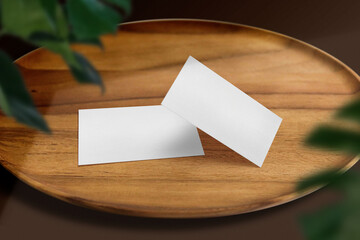 Clean minimal business card mockup on wooden plate and green leaves