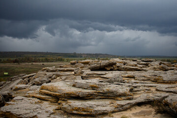 Huge ancient stones of the Stone Tomb megalith on the ground against the background of storm clouds...