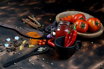red chili and tomato, salt, garlic, rosemary on a dark wooden background; ingredients for cooking; cover cookbook; asian cuisine, free space for text