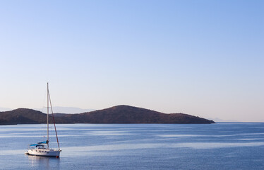 Fototapeta premium Blue sea, a boat and mountains in sunrise. Tranquil seascape and coastal nature concept