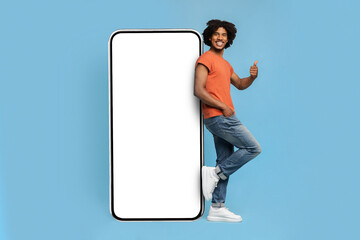 Handsome african american hipster leaning on big cellphone, mockup