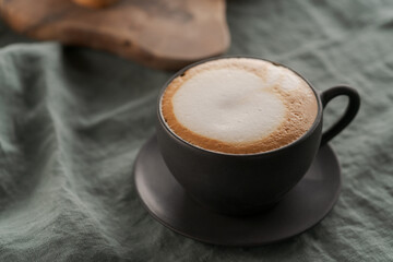 Cappuccino in black cup with ciabatta slices with chocolate spread on background
