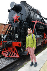 Woman posing on background of steam locomotive
