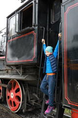 Boy on step of steam locomotive