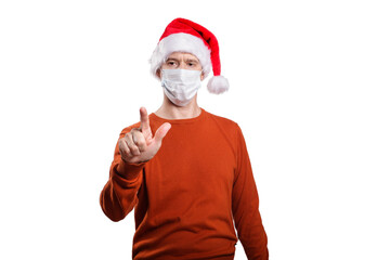 Fototapeta na wymiar an isolated shot of a man in a medical mask, in casual clothes, a Christmas hat. With the finger of his hand he points in front of him, looks at the finger of his hand
