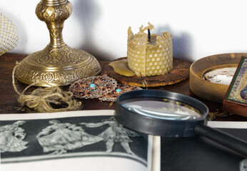 antique items made of bronze, copper, birch bark, a fragment of an illustration and a magnifying glass are out of focus in the foreground