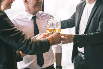 Four business partner celebrating their victory. Old business man making a toss to younger business man and woman. They are holding a champagne glass in a hotel lobby with city scape background.