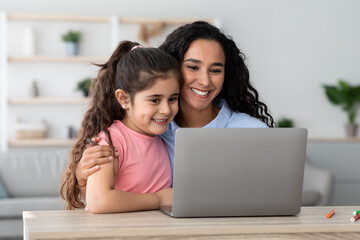 Happy Arab Mom And Little Daughter Using Laptop At Home Together