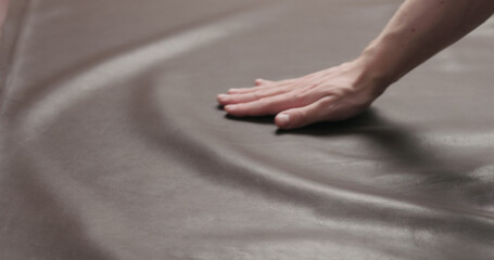 man hand checking brown leather piece closeup