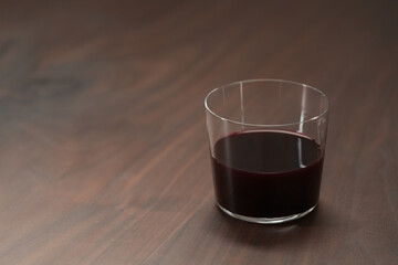 Red wine in tumbler glass on a walnut table with copy space