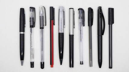 horizontal shot of a group of different types of black pens arranged parallel to each other isolated in a white background