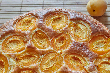 Sweet round pie with apricots on a wooden rustic table