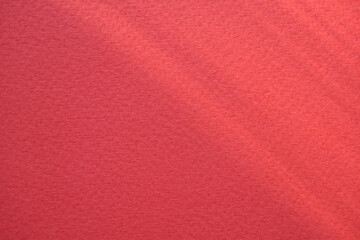 Red velvet paper background in the rays of the sun