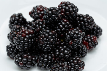 Ripe blackberries on a white plate. Useful forest fruits. Super food. Concept of healthy eating. top view. Close-up. Macro. Blackberry berries with water drops. Flat lay