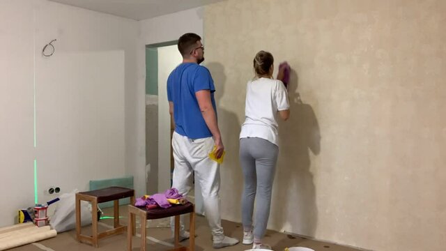 The couple is doing renovations. Husband and wife are doing home repairs. Glue the wallpaper. Fast motion, Time Lapse.
