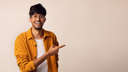 Positive young indian man pointing at copy space