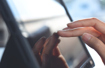 Close up of business woman hand using digital tablet computer surfing the internet, finger touching on tablet screen with reflection on office table, close up
