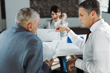 Rear view of mid adult businessman communicating with his colleague during a meeting in the office