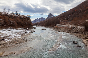 Spring, snow on the banks of a mountain river, forest and mountains, snow melting.