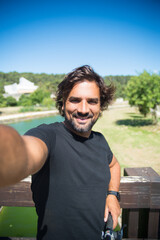 Handsome man taking selfie photo. Person in black t-shirt with bicycle picturing himself in park....