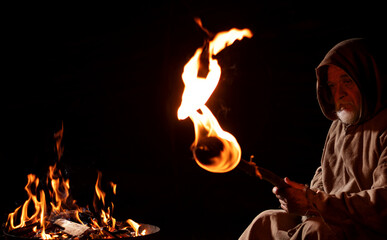 Old medieval man by the fire with torch