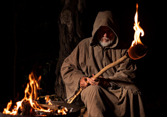 Old medieval monk by the fire with torch - obrazy, fototapety, plakaty