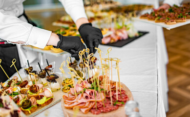 woman hands of a waiter prepare food for a buffet table in a restaurant