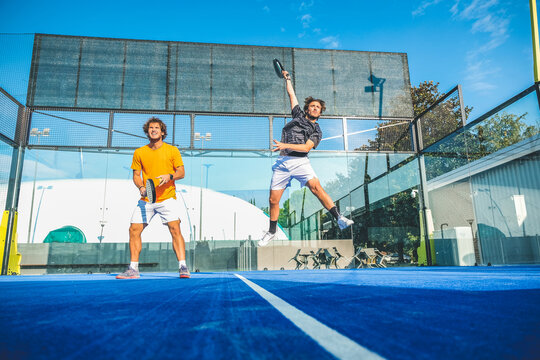 Mixed padel match in a blue grass padel court - Beautiful girl and handsome man playing padel outdoor