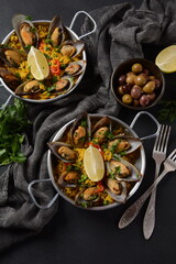 Fototapeta na wymiar Traditional spanish seafood paella in the fry pan. Spanish paella with clamps, mussels, and fresh lemon wedges