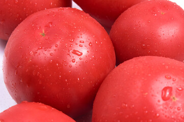 Red juicy close-up. White background. Water drops on wet tomatoes. Selective focus