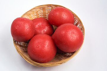 Red tomatoes in a wicker basket on a white background