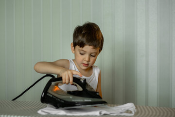 a five-year-old boy helps his mother around the house, the child irons clothes with an iron
