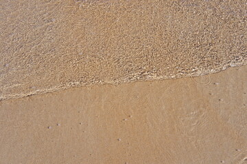 Small wave with sand in a beach