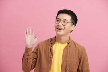 Asian happy young handsome man in casual clothing waving hand greeting say hello hi of goodbye on...
