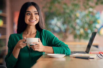 Pretty middle eastern woman student drinking tea at cafe