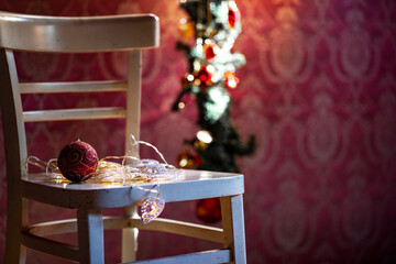 Winter. Christmas decoration on a rustic chair.
Christmas ornament, red - gold color,  with shining lamps.