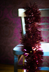 Winter. Christmas decoration on a rustic chair.
Christmas ornament, red - gold color,  with shining lamps.