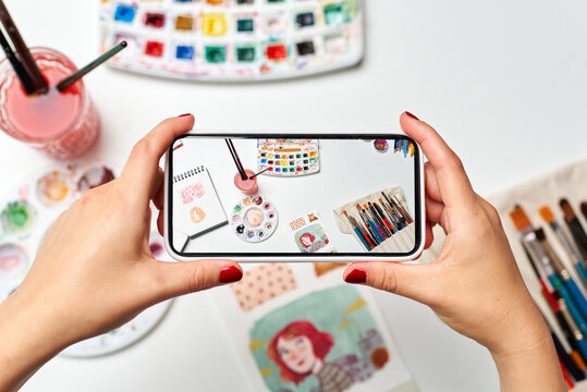 Illustrator woman's hands making a photo of her desk with the mobile phone