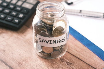 saving coins jar and calculator on table 