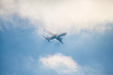 Fototapeta na wymiar Aircraft flying through clouds against a blue sky