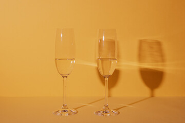 Two glasses of champagne with yellow background and reflected shadows