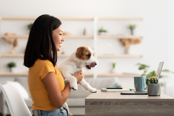 Cheerful japanese woman freelancer working from home with her doggy