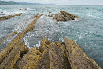 Atlantic ocean coast at low tide in Bay of Biscay. Charming Zumaia Itzurun beach. K-T boundary. Mid-cretaceous period. For  greeting card design, postcard template, touristic guide, magazine, poster.