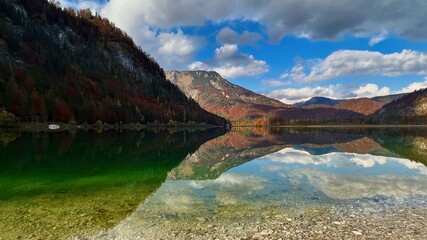Landschaftsaufnahme eines Gebirgssee mit Reflexionen mit Bergen im Hintergrund