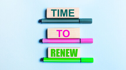 On a light blue background, there are three multi-colored felt-tip pens and wooden blocks with the TIME TO RENEW