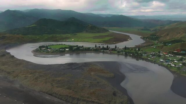 Aerial: Estuary, wild ocean beach, sand dunes and the rural town of Marokopa. Waitomo, New Zealand